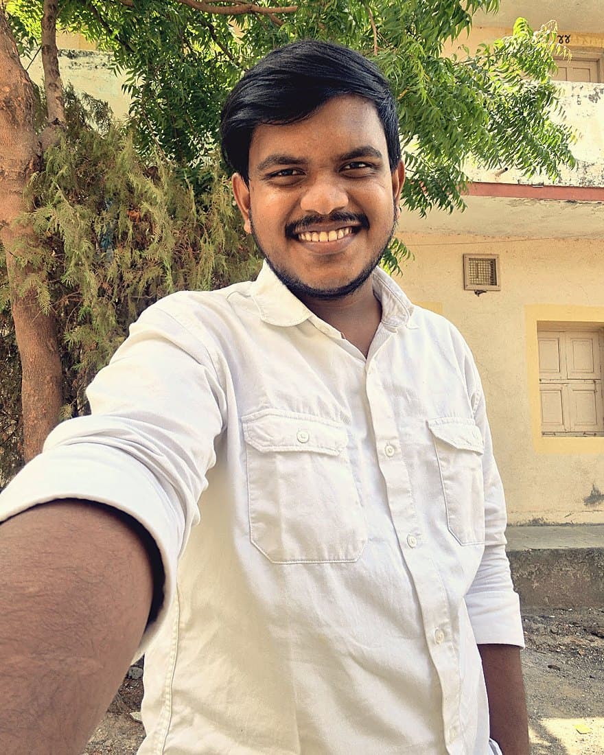 Meet smiling at the camera in a white shirt, outdoors
